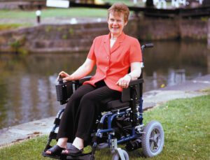 person smiling in an motorised wheelchair outdoors
