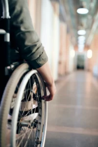 person in wheelchair hands on wheel in a hallway