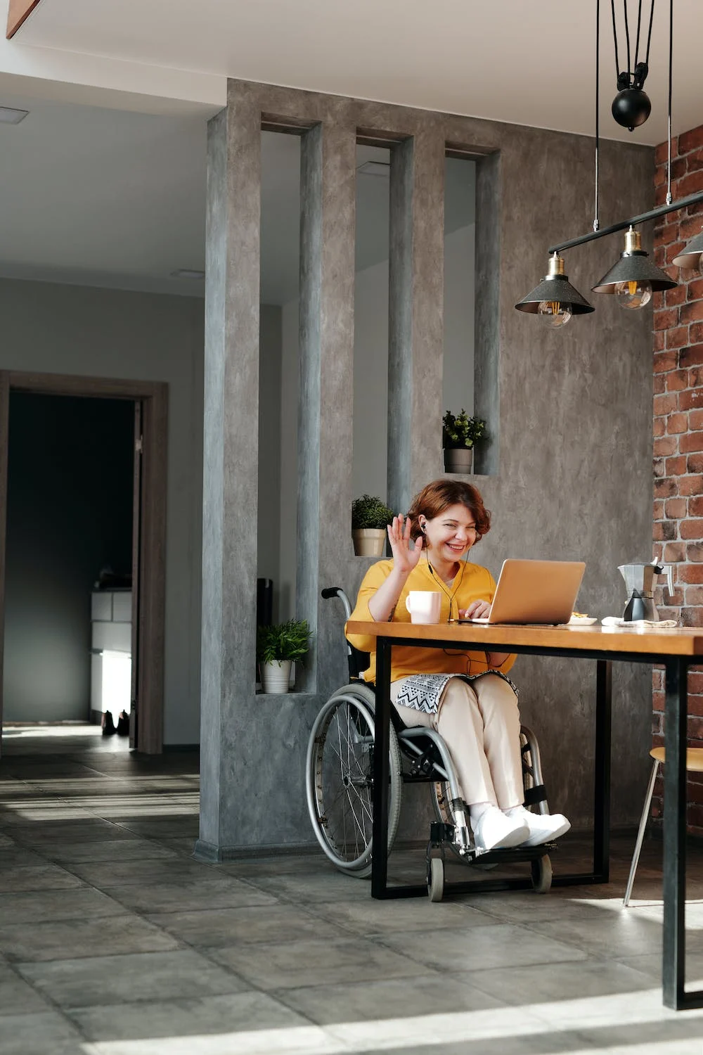 person in a wheelchair at a desk in an office on the laptop