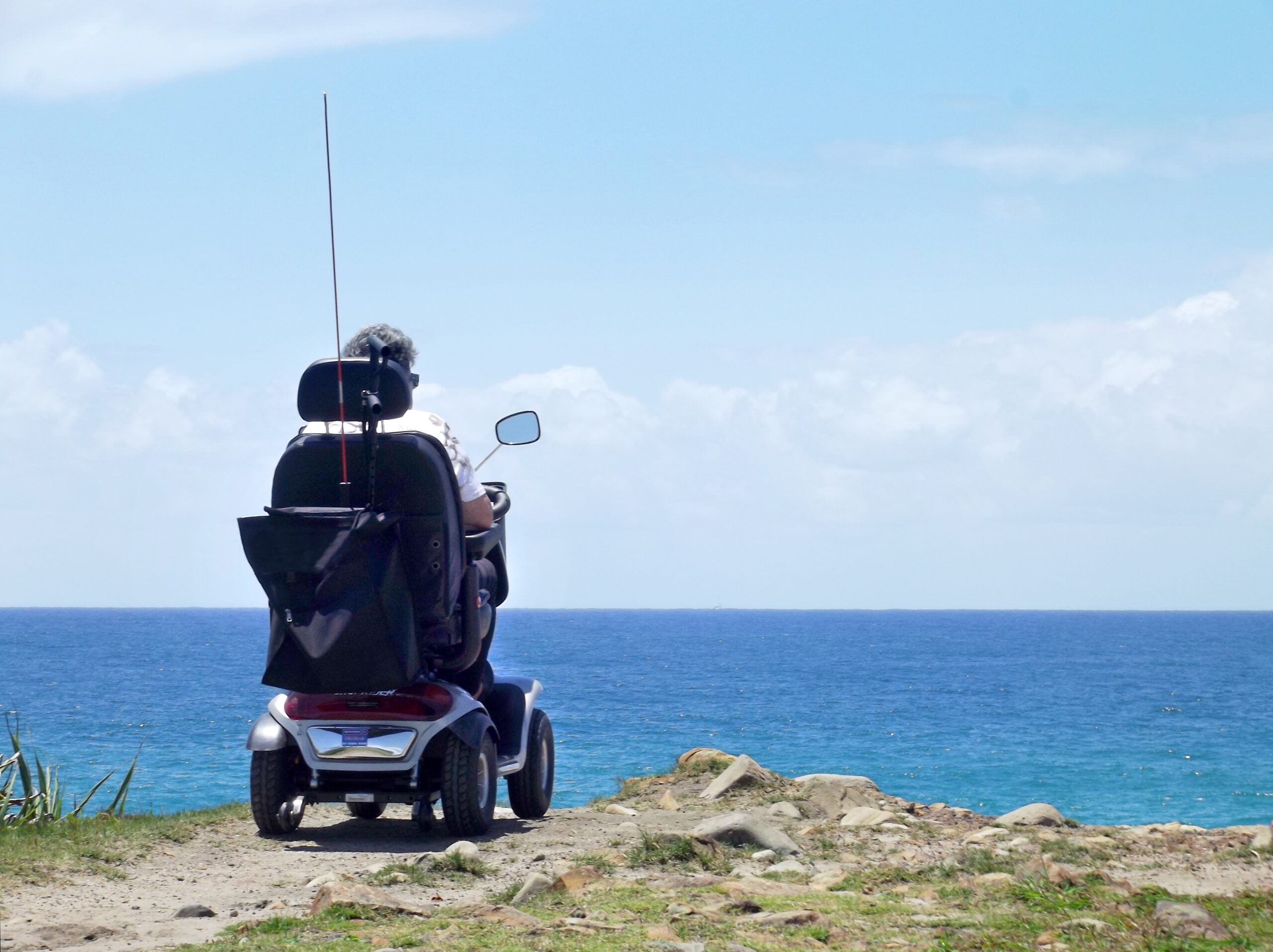 person in electric wheelchair overlooking the coast
