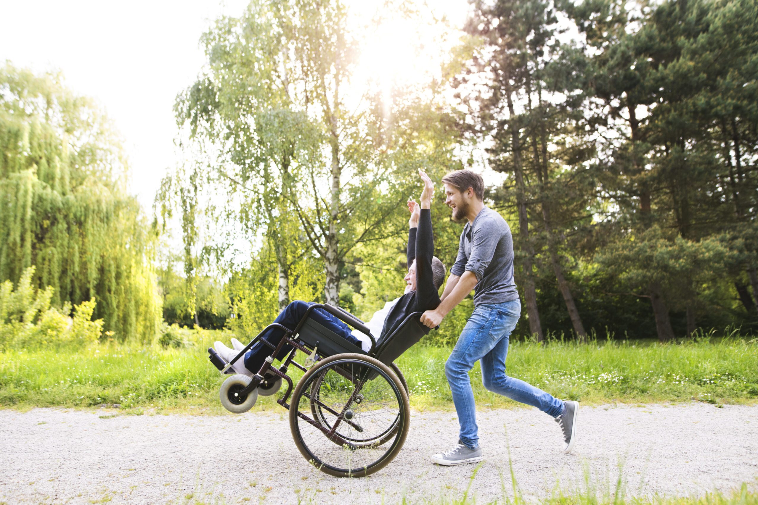 person pushing someone in their wheelchair along a nature pathway
