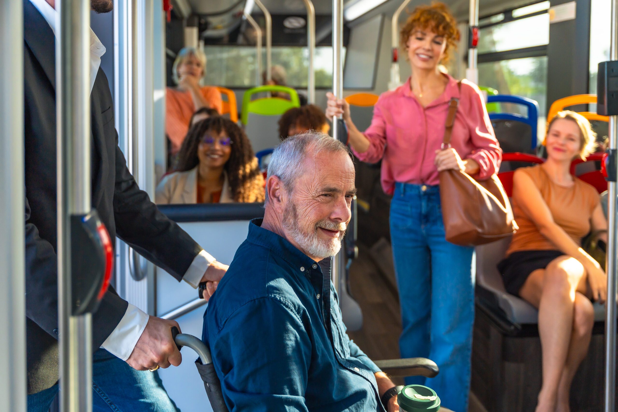 Man in a wheelchair being assisted on a public transit bus, representing accessibility and independent living while traveling safely with fellow passengers
