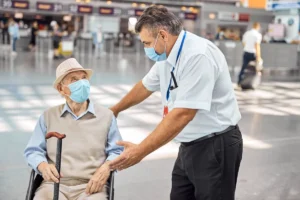 elderly man in airport with wheelchair being assisted